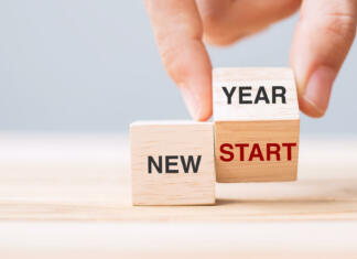 Kje in kako silvestrovati? hand flip wooden block with New Year to New Start text on table background. Resolution, strategy, solution, goal, business and holiday concepts