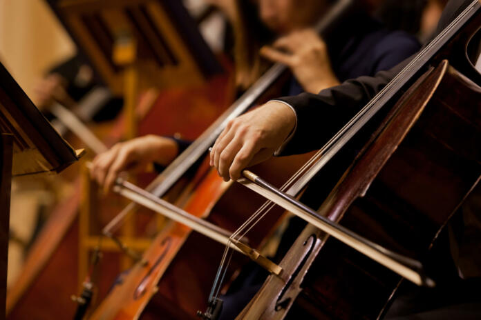 Hands of the man playing the cello in dark colors