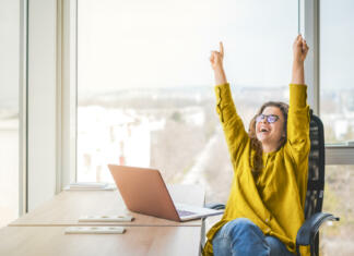 Nutelina torta Happy successful businesswoman in yellow shirt raising fists with ambition. Woman going up career ladder. Business achievement and promotion concept