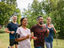 Healthy group of multiethnic middle aged men and women jogging at park. Happy mixed race couples running together. Mature friends running together outdoor.