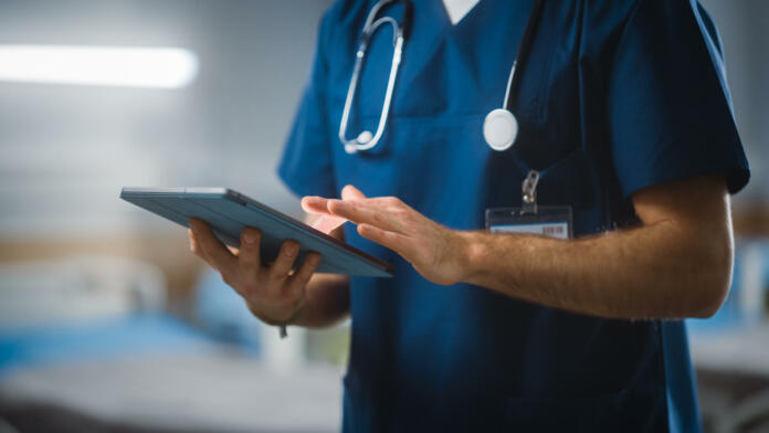 hospital-ward-unrecognizable-head-nurse-doctor-surgeon-uses-digital-tablet-computer-health-care-vitals-monitoring-computer-machine-modern-clinic-with-advanced-equipment-and-professional-working-stockpack-istock Hospital Ward: Unrecognizable Head Nurse, Doctor, Surgeon Uses Digital Tablet Computer Health Care Vitals Monitoring Computer Machine. Modern Clinic with Advanced Equipment and Professional Working