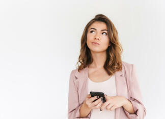 TOMO KRIŽNAR: Začutite življenje v vsej njegovi lepoti in razmišljajte širše! Image of young cute beautiful lady standing isolated over white wall background looking aside using mobile phone.