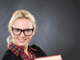Inteligent woman in glasses with books.Black background.