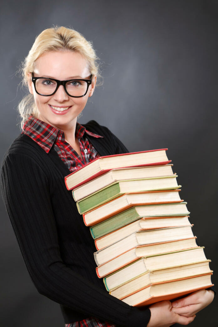 Inteligent woman in glasses with books.Black background.