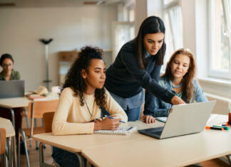 Matic Užmah IT teacher and her students using laptop during computer class in high school.