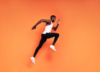 Samozavest?! KAJ JE TO? Male runner doing fitness workout. Athlete exercising over an orange background.