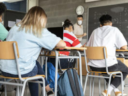 Mathematics class. Mature white male teacher wearing face mask in classroom with group of multiracial teen high school students. Education concept. Healthcare concept.