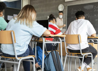 Enkrat je dovoljeno ponavljanje Mathematics class. Mature white male teacher wearing face mask in classroom with group of multiracial teen high school students. Education concept. Healthcare concept.