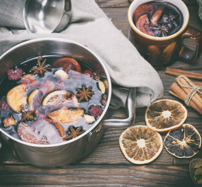 mulled wine in an iron saucepan on a brown wooden table, top view