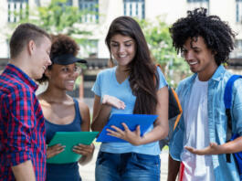 Multi ethnic male and female students in discussion outdoor in summer in city