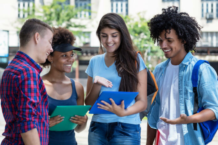 Multi ethnic male and female students in discussion outdoor in summer in city