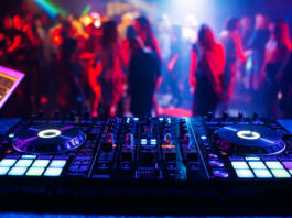 music controller DJ mixer in a nightclub at a party against the background of blurred silhouettes of dancing people