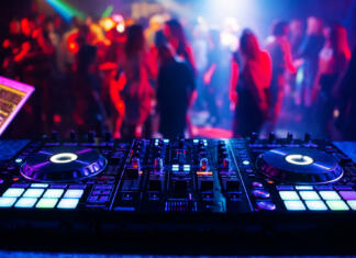 V torek že 17. Študentsko pustovanje music controller DJ mixer in a nightclub at a party against the background of blurred silhouettes of dancing people