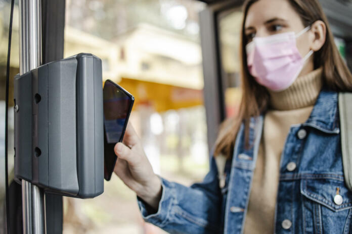 Photo of a woman driving in the bus and paying for a ticket with smart phone