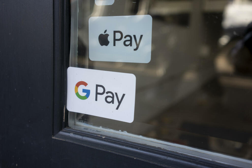 Portland, OR, USA - Nov 8, 2021: Google Pay and Apple Pay stickers are seen at the entrance to a retail store in northwest Portland, Oregon.