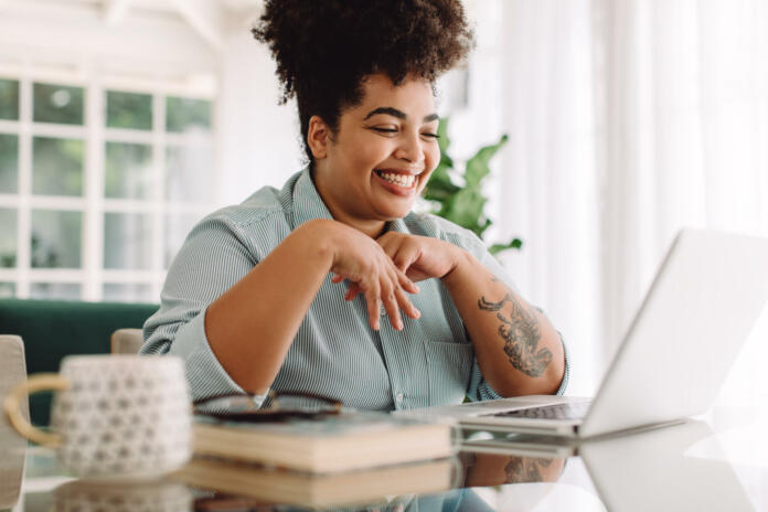 Positive woman video calling using laptop. Businesswoman teleconferencing on laptop while working from home.