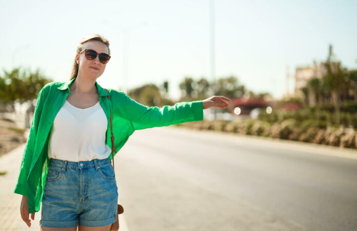 Pretty woman hitch-hiking on the roadside.