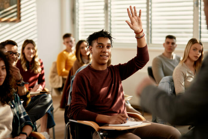smiling-african-american-student-raising-his-hand-to-ask-a-questing-during-a-class-at-lecture-hall-stockpack-istock Smiling African American student raising his hand to ask a questing during a at lecture hall.