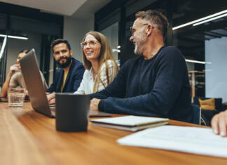 Zavod Ypsilon v januarju 2017 Successful group of businesspeople having a briefing in a boardroom. Happy businesspeople smiling while working together in a modern workplace. Diverse business colleagues collaborating on a project.
