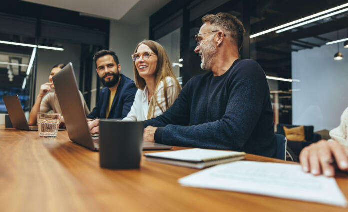 Successful group of businesspeople having a briefing in a boardroom. Happy businesspeople smiling while working together in a modern workplace. Diverse business colleagues collaborating on a project.