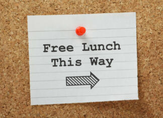 BREZPLAČNO kosilo prejmejo… The phrase Free Lunch This Way typed on a piece of lined paper and pinned to a cork notice board