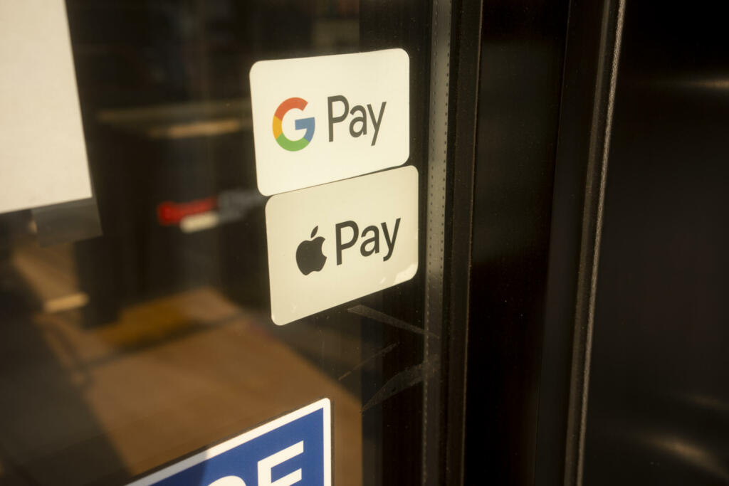 Tigard, OR, USA - Sep 3, 2021: Google Pay and Apple Pay stickers are seen at the entrance to a shop in Tigard, Oregon.