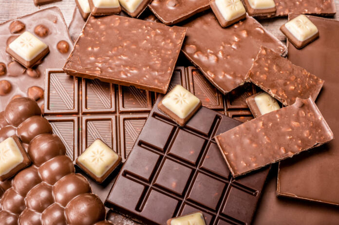 Top view of arrangement of various types of chocolate. Delicious chocolate mix. Top view of pieces of chocolate bar with chips. bar with scattered pieces