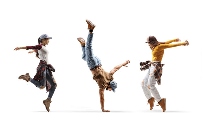 Two female dancers and one male dancer performing a hand stand isolated on white background