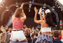 Poletni festivali: kako se jih udeležiti čim bolj poceni na praktičnem primeru Two girls on shoulders in the crowd at a music festival