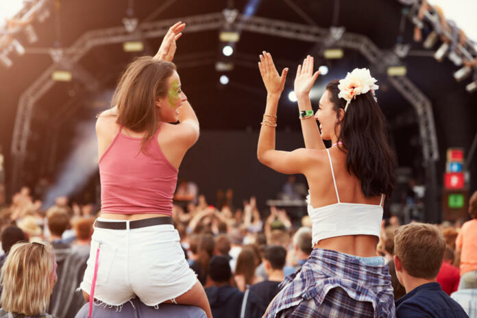 Two girls on shoulders in the crowd at a music festival