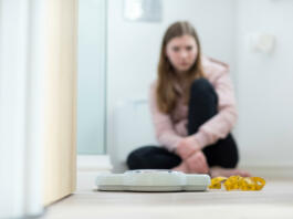 Unhappy Teenage Girl Sitting In Bathroom Looking At Scales And Tape Measure