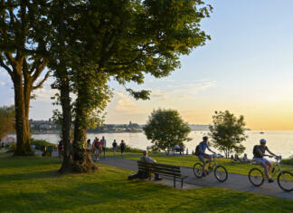 Brezplačna rekreacija za študente Vancouver, B.C., Canada - July 18, 2012: Young couple cycling, others walking or jogging late afternoon and enjoying the sunset at Stanley Park