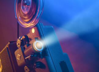 Prikrita skrivnost Vintage old fashioned projector in a dark room projecting a film, cinematography concept