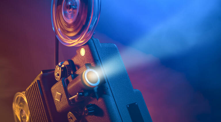 Vintage old fashioned projector in a dark room projecting a film, cinematography concept