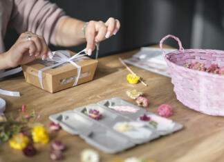 Ustvarjajmo darila sami woman packing box with handmade candles. DIY gift concept. young woman entrepreneur earns on her creativity