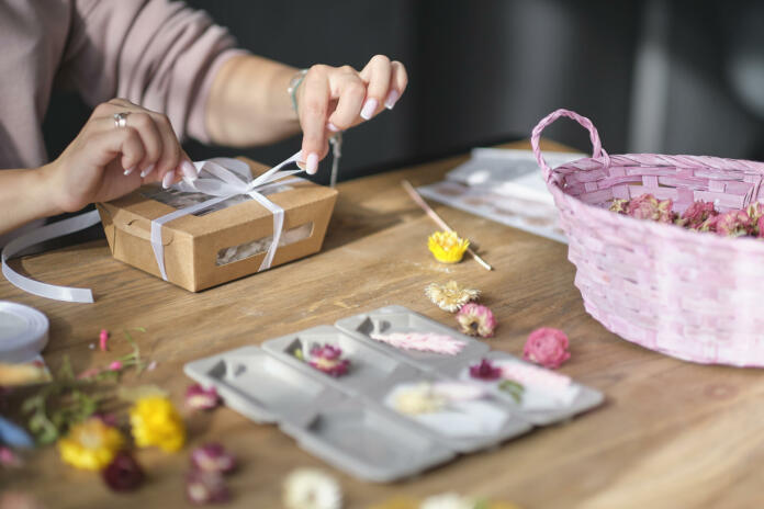 woman packing box with handmade candles. DIY gift concept. young woman entrepreneur earns on her creativity