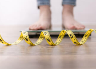 Šport + zdrava prehrana Women's legs on the scales, close-up of a measuring tape, the concept of losing weight, healthy lifestyle.