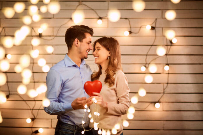 Young couple on Valentine's Day. A loving couple hugs against a background of glowing garlands.