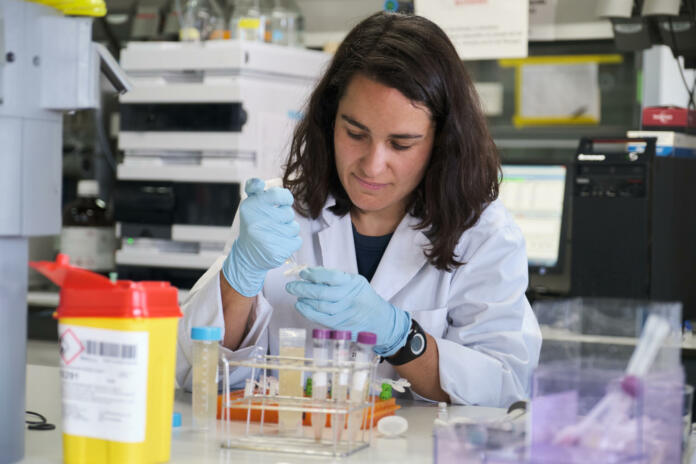 Young female researcher working in a real laboratory analysing experimental samples.