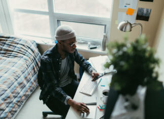 Subvencije za stanovanja Young man working at his desk in his bedroom.
