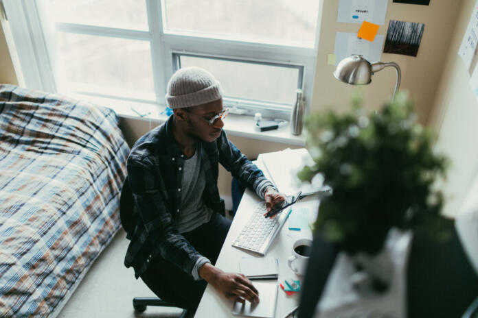 Young man working at his desk in his bedroom.