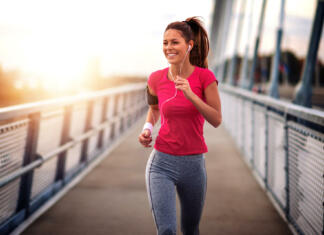 S športnimi aktivnostmi do več energije Young woman jogging outdoors on bridge. Concept of healthy lifestyle.