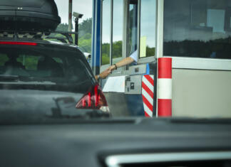 Osvoji brezplačno vinjeto 2021! A man pays money to a cashier for a toll road Toll gate motorway entrance