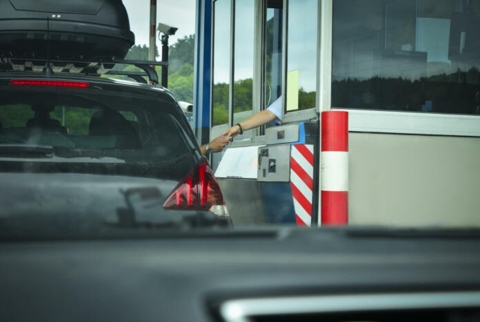 A man pays money to a cashier for a toll road Toll gate motorway entrance