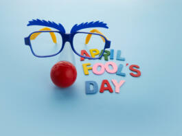 April Fools Day text and funny glasses on blue background.