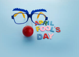 April Fools Day text and funny glasses on blue background.