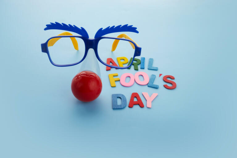 April Fools Day text and funny glasses on blue background.