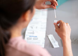 Hitro testiranje tudi za študente Asian woman using rapid antigen test kit for self test COVID-19 epidemic at home. Adult female place the fabric tip of the swab in the extraction tube and rolling around the tube. COVID-19 pandemic protection concept.