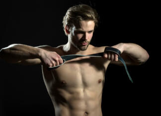 Vodič po BDSM, kaj sploh je in nasveti Belt in hands of naked man. The guy does exercises for hands with leather belt. Sexy model for men's accessories. Concentration and meditation in the gym