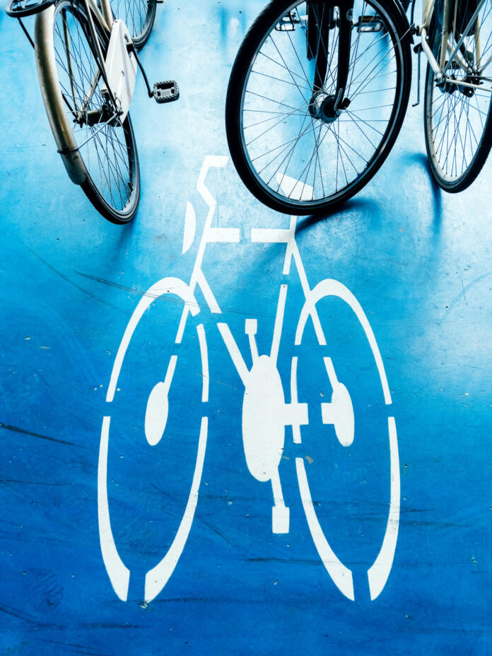 Bicycle parking area with bike pictogram symbol on ground and wheels in the background